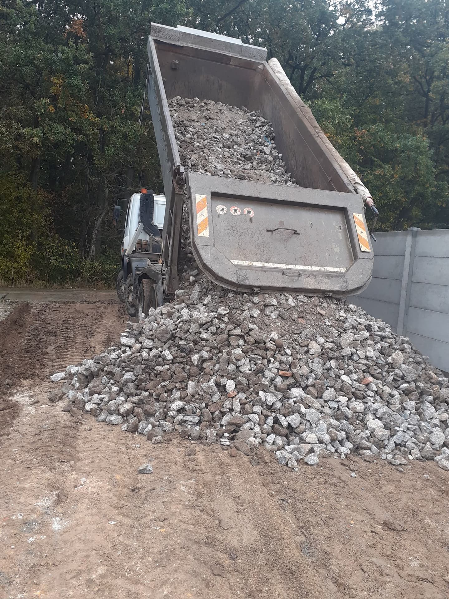 Autobasculantă descarcă piatră spartă pentru o platformă sau un drum de acces pe un teren pregătit