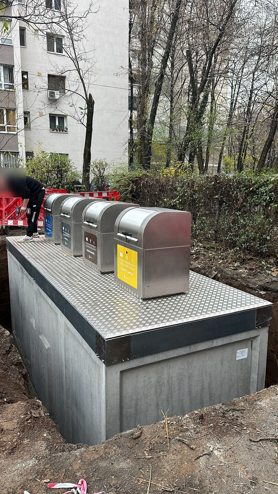 Cuvă prefabricată din beton cu patru containere de inox, așezată în groapa săpată lângă un bloc