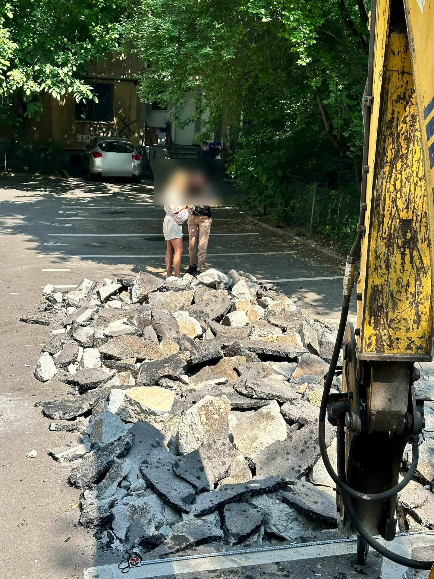 Asfalt spart cu ciocanul hidraulic montat pe buldoexcavator, strâns grămadă într-o parcare
